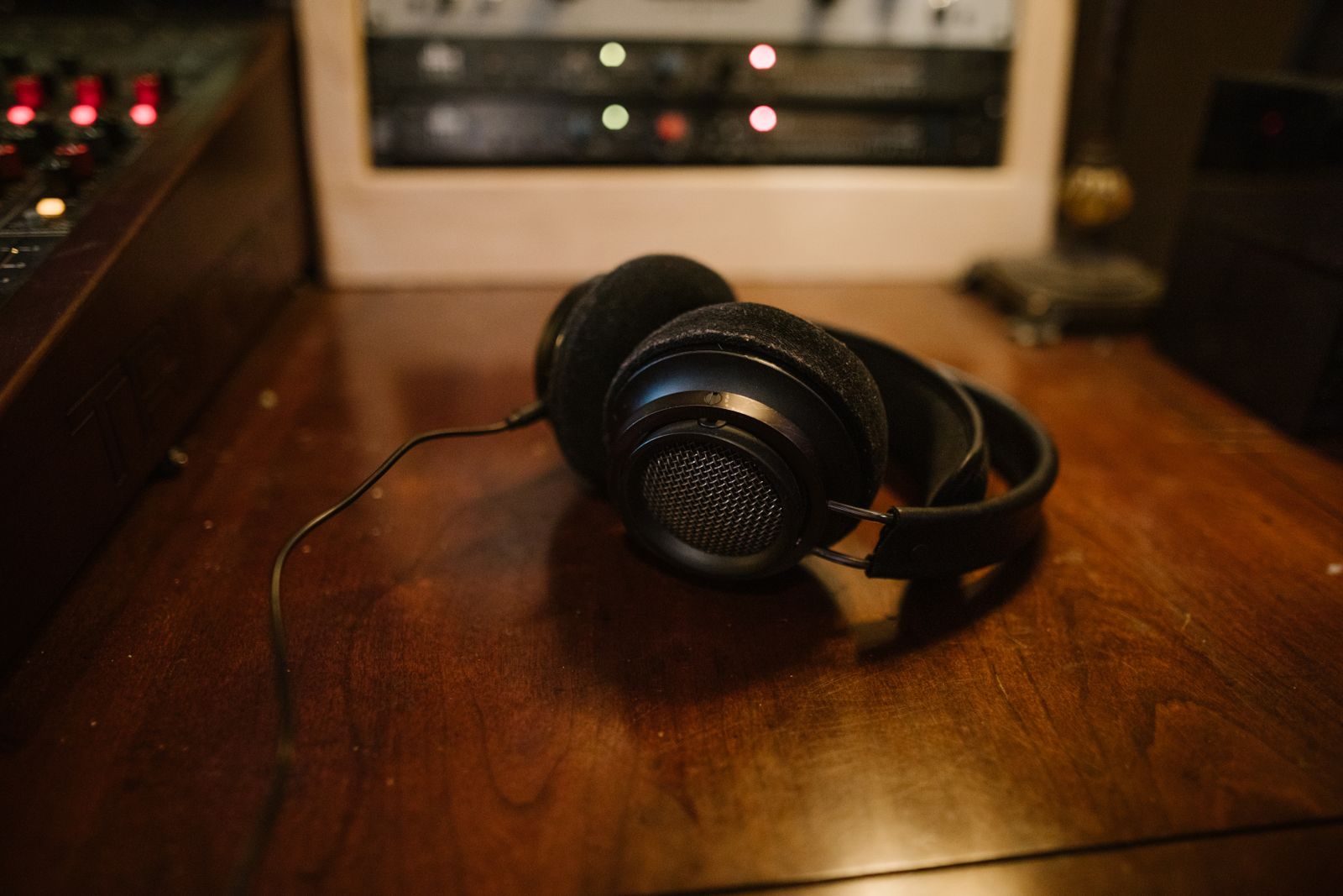 Black over-ear headphones resting on a wooden studio desk