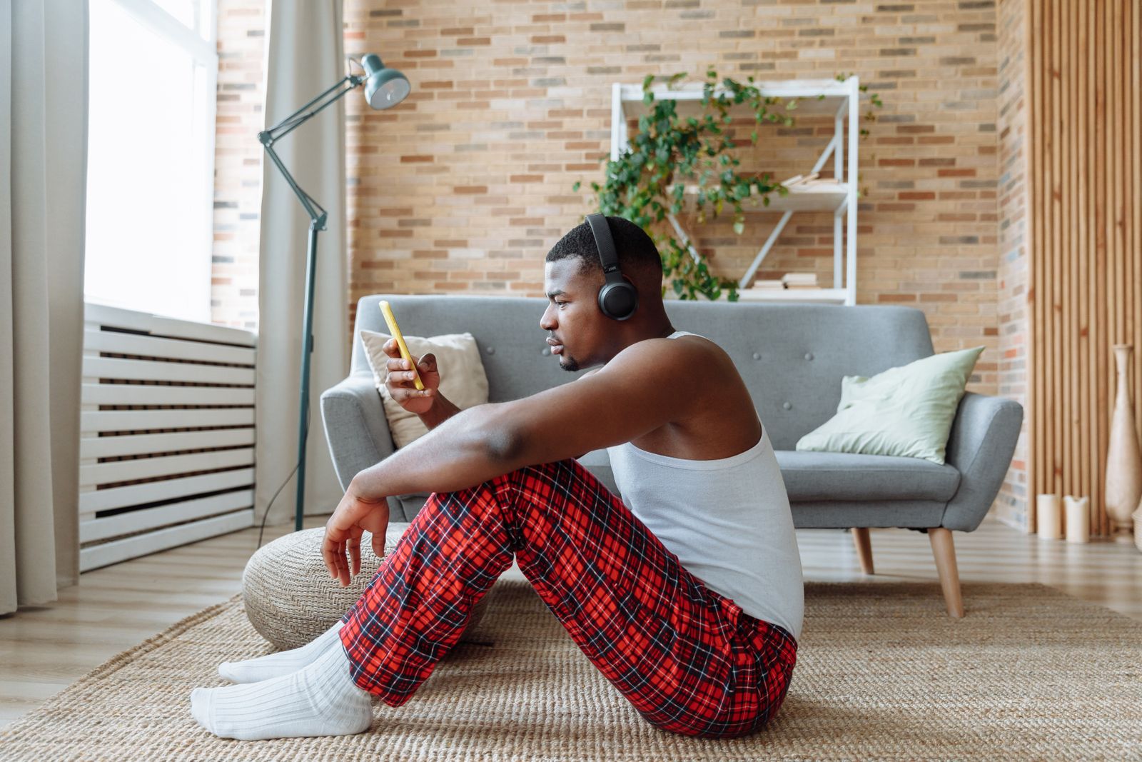 Listener with headphones and a phone beside a sofa