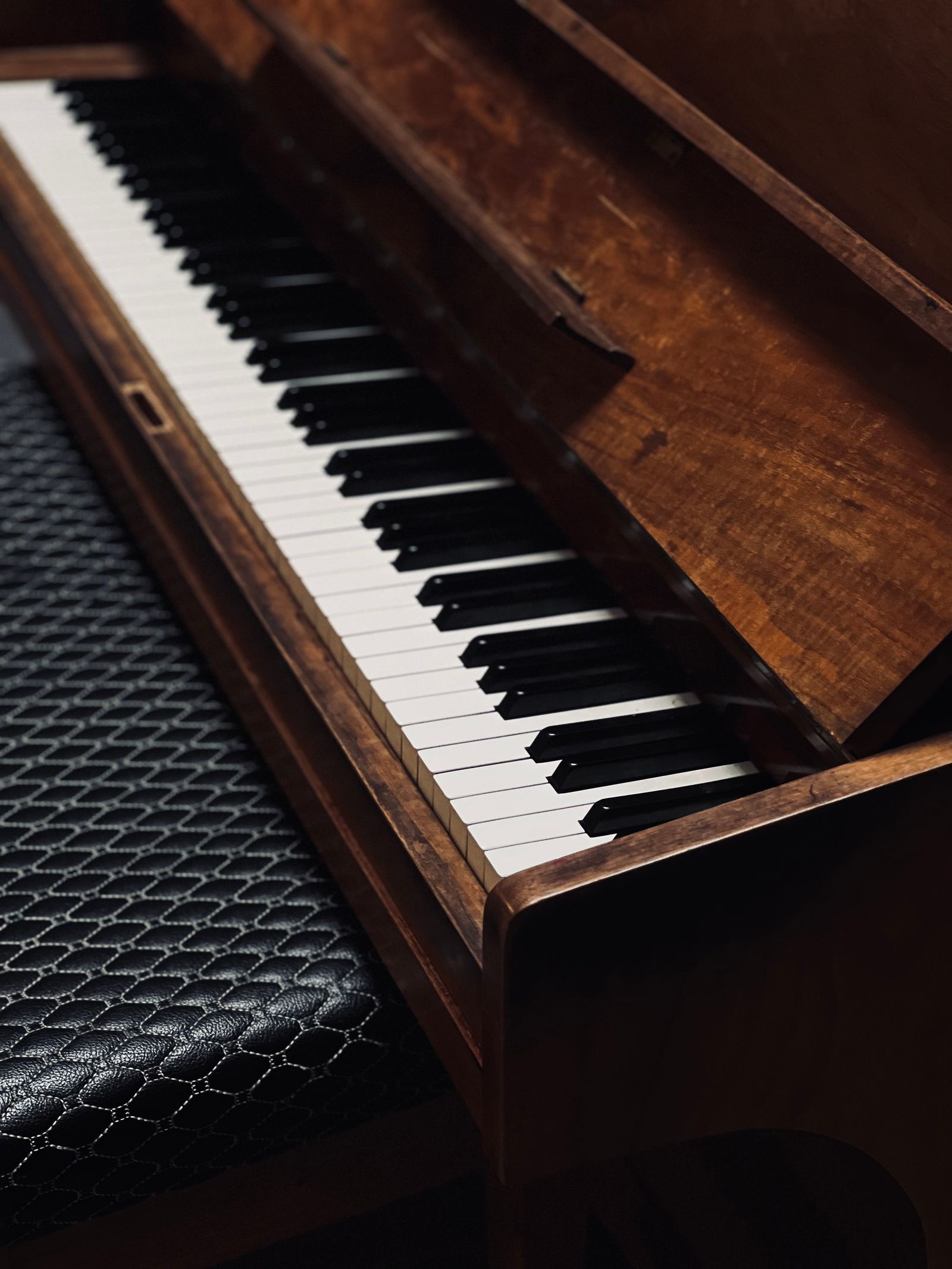 Piano keyboard beside a padded bench